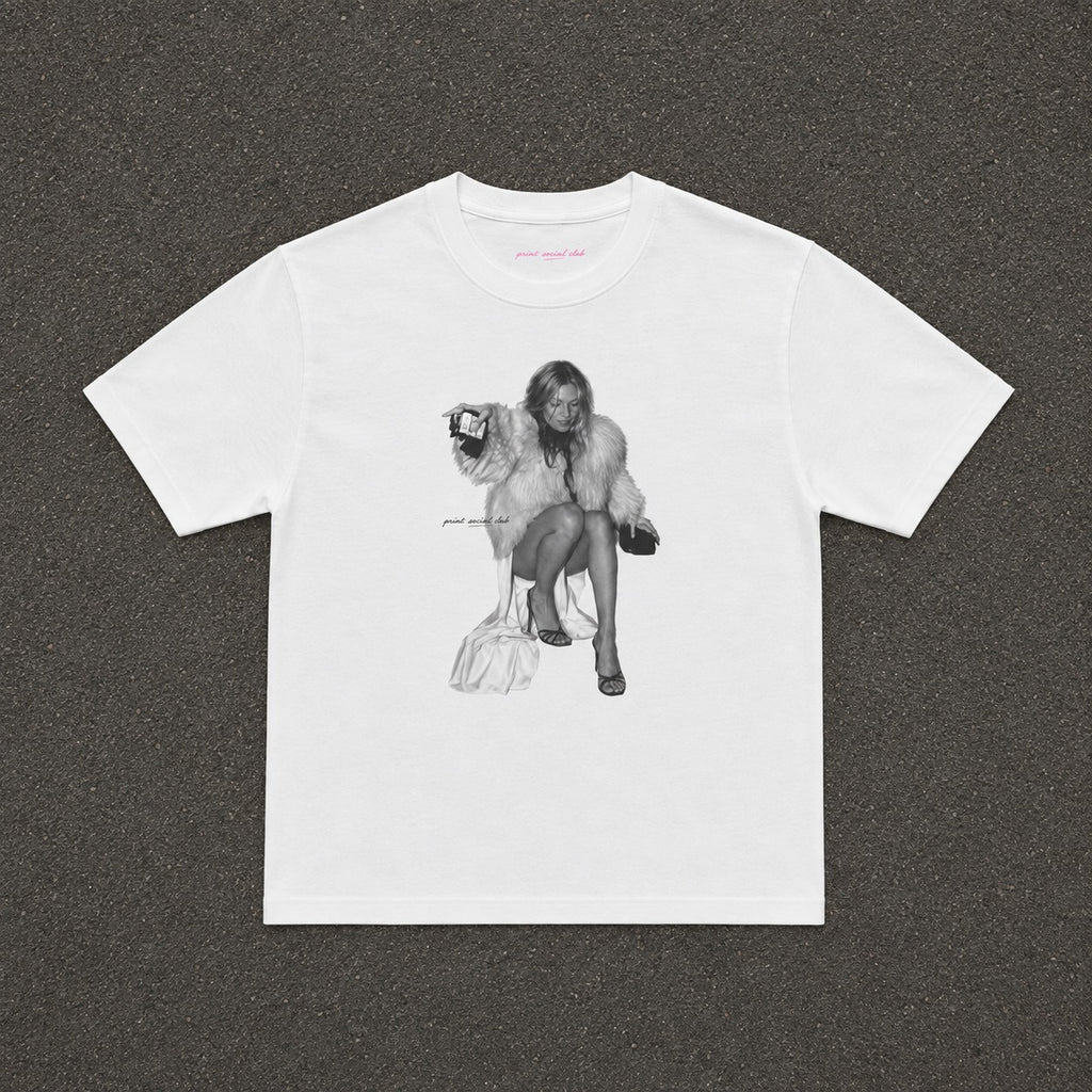 Moss Baby Tee in white, flat lay with a black and white fur coat portrait print