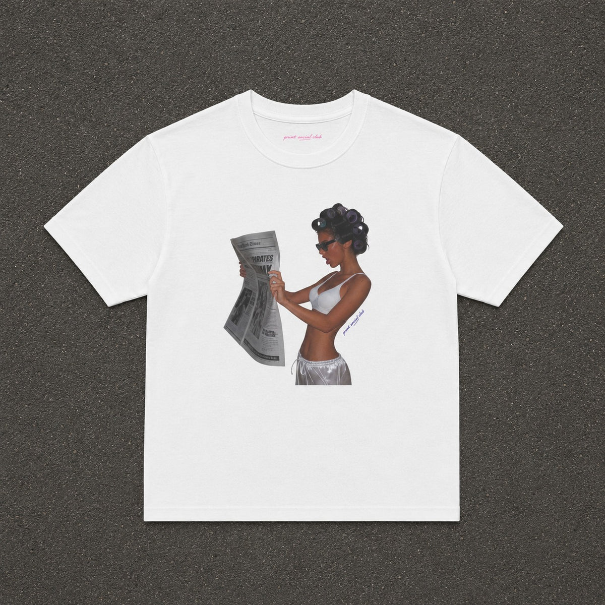 News Baby Tee in white, flat lay with a black and white newspaper reader print